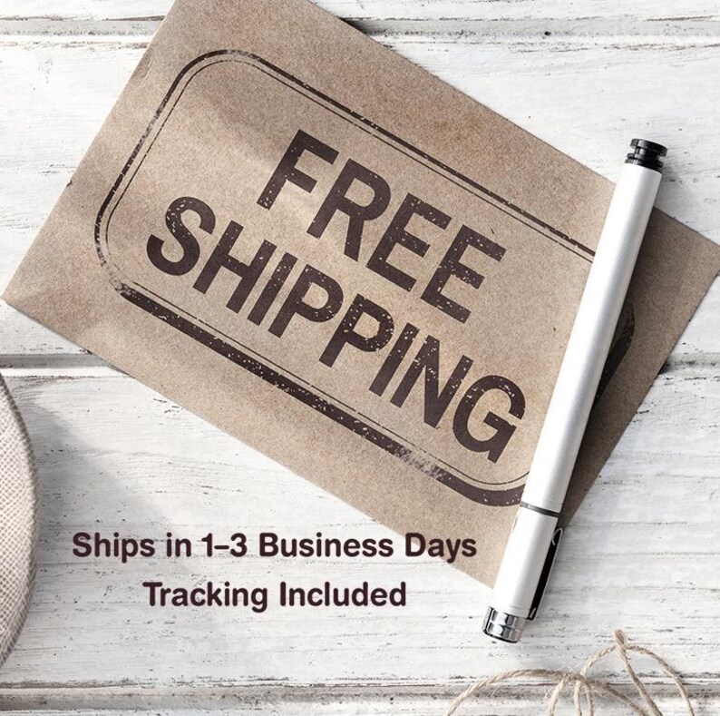 May include: A brown paper tag with the words "FREE SHIPPING" in large, bold, black letters. A white pen rests on the tag. The background is a white, weathered wood surface.