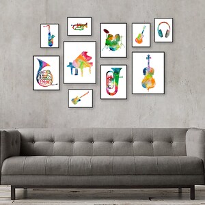 K&ouml;nnte beinhalten: Ein Set aus 10 bunten Aquarelldrucken mit verschiedenen Musikinstrumenten, darunter ein Saxophon, eine Trompete, ein Klavier, ein Schlagzeug, eine Gitarre, ein Cello, ein Waldhorn und ein Bass. Die Drucke sind in Schwarz gerahmt und an einer grauen Wand &uuml;ber einem grauen Sofa angeordnet.