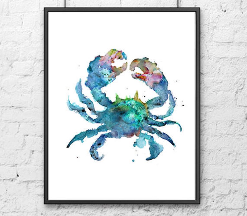 May include: Watercolor painting of a crab in shades of blue, green, and pink. The crab is centered on a white background, framed in a black border. The artwork is a decorative piece.