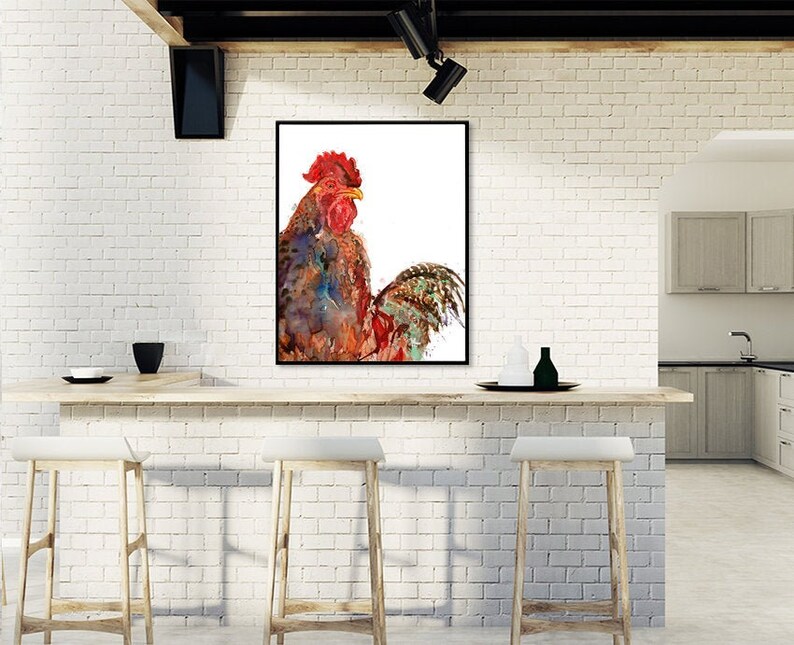 May include: A framed watercolor painting of a rooster. The rooster has a red comb and wattle, with a body of blue, brown, and orange hues. The artwork is displayed on a white brick wall above a wooden bar with stools.