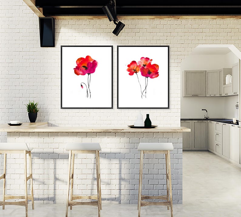 May include: Two framed watercolour paintings of red poppies on a white background. The paintings are hanging on a white brick wall above a wooden countertop.