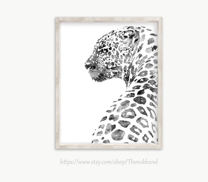 K&ouml;nnte beinhalten: Ein gerahmter Kunstdruck mit einer schwarz-wei&szlig;en Aquarellillustration eines Leoparden im Profil, der nach links blickt. Der Leopard hat detaillierte dunkle Flecken auf wei&szlig;em Hintergrund und ist in einem hellen Holzrahmen gefasst.