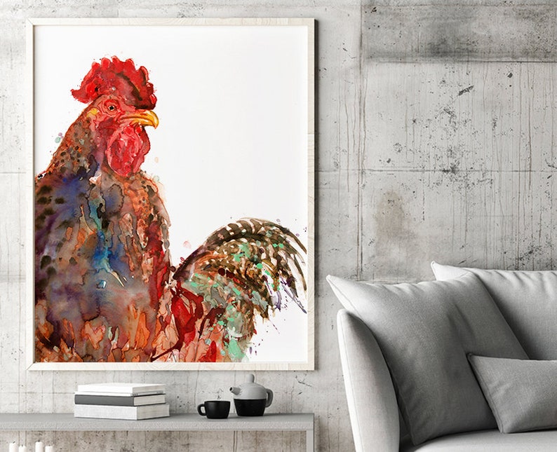 May include: Watercolor painting of a rooster in a white frame. The rooster has red, brown, blue, and green feathers. The artwork is displayed on a gray shelf with books, a teapot, and cups. The background is a gray concrete wall.