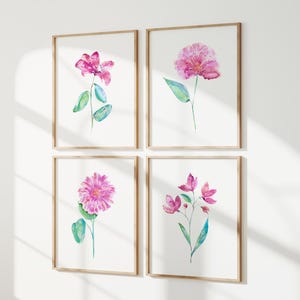 May include: A set of four framed wall art prints featuring watercolor illustrations of pink flowers with green stems and leaves. Each print is encased in a light-colored wooden frame, displaying distinct floral arrangements on a white background.