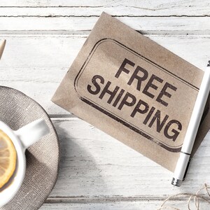 K&ouml;nnte beinhalten: Ein brauner Papierumschlag mit dem Stempel "FREE SHIPPING" in schwarzer Tinte. Ein wei&szlig;er Stift liegt auf dem Umschlag.