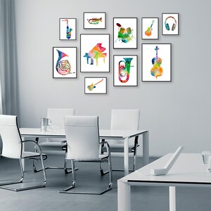 K&ouml;nnte beinhalten: Ein wei&szlig;er Esstisch mit vier wei&szlig;en St&uuml;hlen und ein wei&szlig;er Schreibtisch mit einem Laptop und einem Telefon darauf. Die Wand hinter dem Tisch ist mit neun gerahmten Aquarellbildern von Musikinstrumenten dekoriert, darunter ein Saxophon, eine Trompete, ein Klavier, eine Tuba, ein Cello, eine Gitarre, ein Schlagzeug, ein Kopfh&ouml;rer und eine Gitarre.