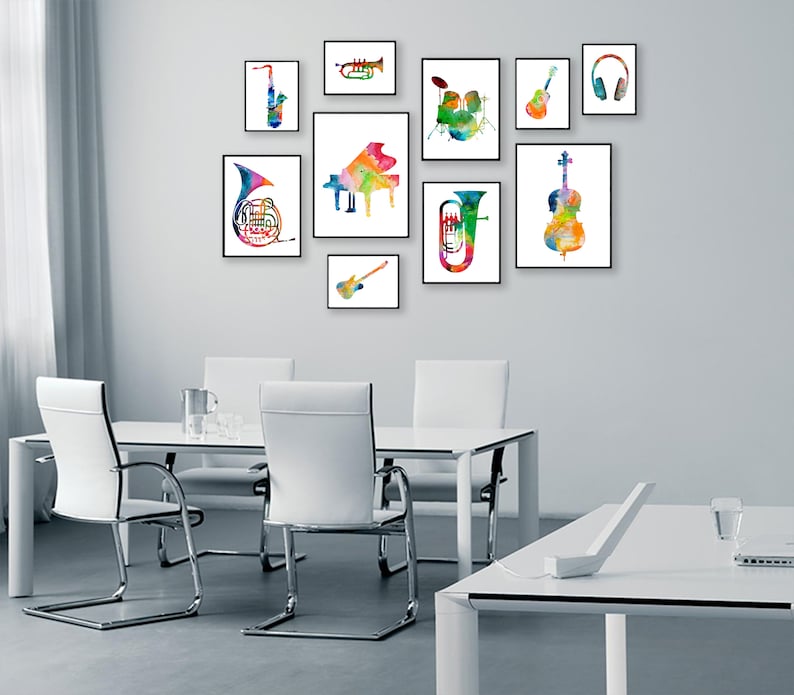 K&ouml;nnte beinhalten: Ein wei&szlig;er Esstisch mit vier wei&szlig;en St&uuml;hlen und ein wei&szlig;er Schreibtisch mit einem Laptop und einem Telefon darauf. Die Wand hinter dem Tisch ist mit neun gerahmten Aquarellbildern von Musikinstrumenten dekoriert, darunter ein Saxophon, eine Trompete, ein Klavier, eine Tuba, ein Cello, eine Gitarre, ein Schlagzeug, ein Kopfh&ouml;rer und eine Gitarre.