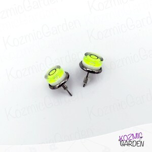 A pair of silver stud earrings with a small, round, yellow and white spirit level bubble in the centre of each earring.