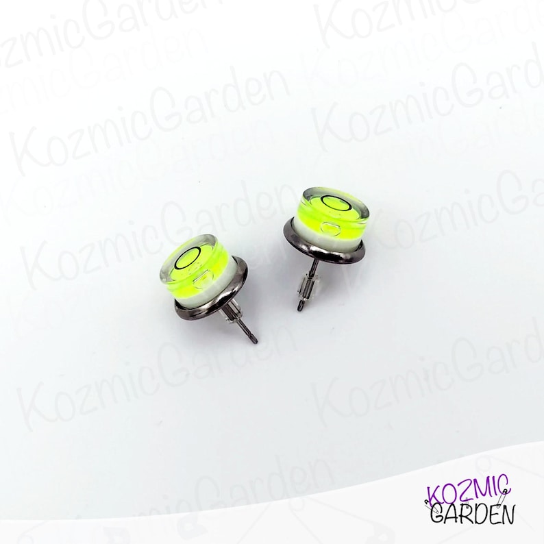 A pair of silver stud earrings with a small, round, yellow and white spirit level bubble in the centre of each earring.