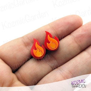 Puede incluir: Un par de pendientes de llama roja con un diseño de llama amarilla y naranja.