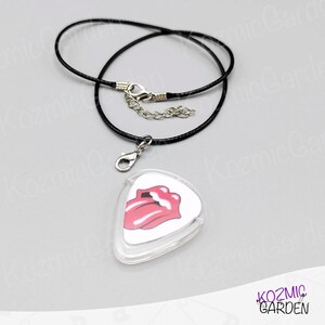 May include: A black cord necklace with a silver clasp and a guitar pick pendant. The pendant has a white background and a pink tongue and lips graphic.