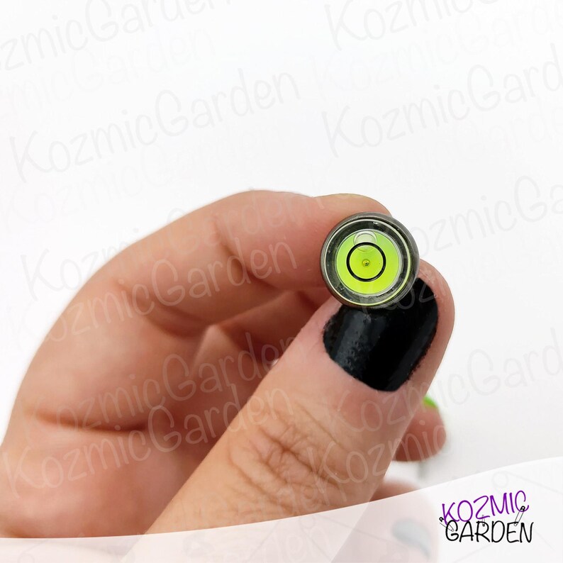 A close-up of a small, round level with a green bubble in the centre. The level is made of metal and has a black rim.