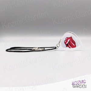 May include: A clear, guitar pick-shaped pendant with the famous red lips logo. It hangs from a black cord necklace with a silver-coloured clasp. The design is a tribute to rock music.