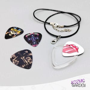May include: A selection of guitar plectrums with band logos and a Rolling Stones tongue design. Includes a black cord necklace with a clasp and a clear pick holder. The plectrums feature various colours and designs.