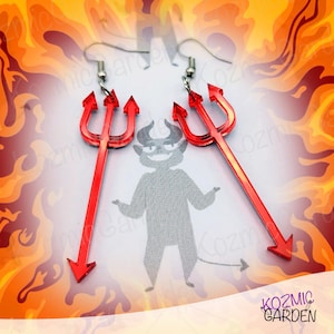 Puede incluir: Pendientes de tridente rojo de diablo con ganchos plateados. Los pendientes están hechos de un material rojo transparente y tienen forma de tridente. El fondo presenta un diablo de dibujos animados y llamas, con el texto "Kozmic Garden".