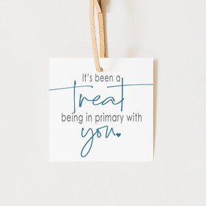 May include: A white card with blue text that reads "It's been a treat being in primary with you." A small blue heart is next to the word "you". The card is hanging from a piece of twine.