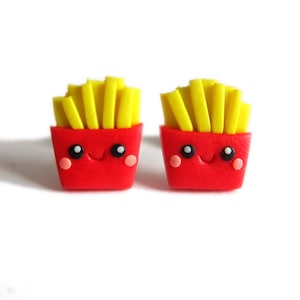 Peut inclure: Une paire de boucles d'oreilles en forme de frites rouges et jaunes avec un visage de dessin animé mignon. Les boucles d'oreilles sont en pâte polymère.