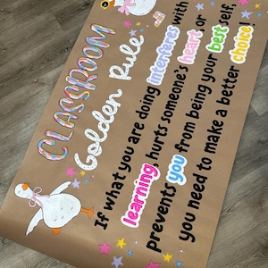 May include: A brown paper poster featuring two white geese with pink bows and the text: Classroom Golden Rule: If what you are doing interferes with learning, hurts someone's heart, or prevents you from being your best self, you need to make a better choice!