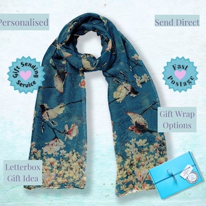 May include: A teal blue scarf with a floral and bird print. The scarf is folded and displayed on a white background. The text "Send Direct", "Fast Postage", "Gift Wrap Options", "Letterbox Gift Idea", "Personalised", and "Gift Sending Service" is visible in the image.