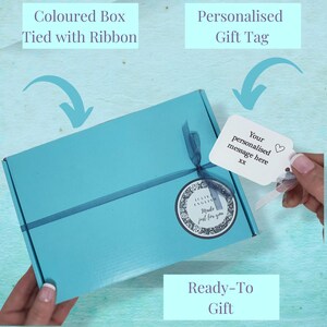 May include: A light blue gift box tied with a ribbon and a white gift tag with the text "Your personalised message here" and a heart symbol. The box is ready to be given as a gift.