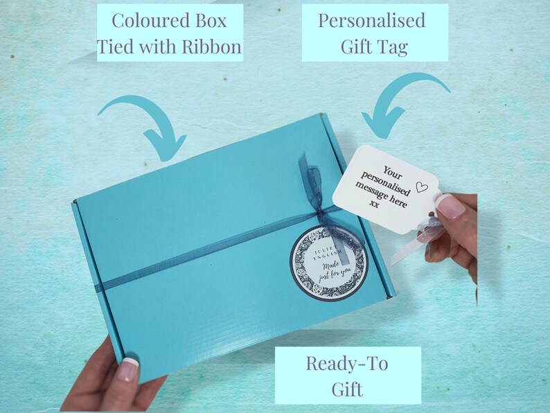 May include: A light blue gift box tied with a ribbon and a white gift tag with the text "Your personalised message here" and a heart symbol. The box is ready to be given as a gift.