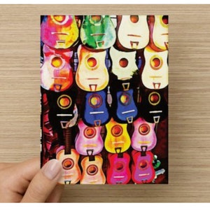 May include: A wall display of colorful acoustic guitars with various shades of blue, green, red, yellow, and white. The guitars are arranged in rows, creating a vibrant and eye-catching pattern.