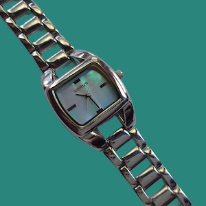 May include: A silver-toned Lorus wristwatch with a rectangular face and a mother-of-pearl dial. The watch has a linked band and a small crown. The watch face displays the Lorus brand name.