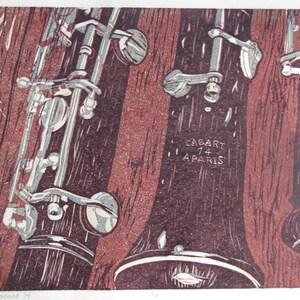 May include: A close-up of two antique oboes with silver keys and a wooden body. The oboes are resting on a wooden surface. The text "CABART 74 PARIS" is visible on one of the oboes.