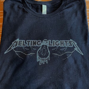 May include: Black t-shirt with a white graphic of a melting light bulb with the text "Melting Lights" in a stylized font.