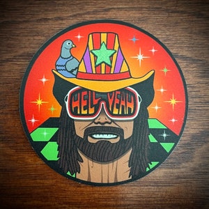 May include: A colorful illustration of a wrestler wearing a yellow cowboy hat with a multi-colored stripe pattern, sunglasses that say "Hell Yeah", and a long black beard. The background is a red and orange gradient with white stars and a green and white checkered pattern.
