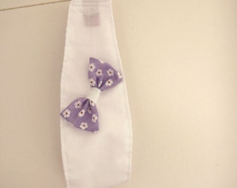 White fabrice headband with a purple daisy print bow with a white central tie.