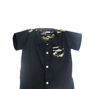 Puede incluir: Camisa negra de manga corta con botones y estampado de taxi amarillo en el interior del cuello y el bolsillo.