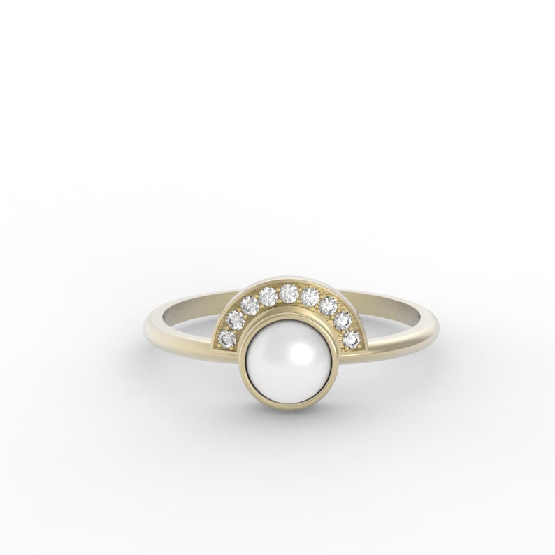 May include: A gold ring with a white pearl set in a bezel setting. The pearl is surrounded by a half circle of small diamonds.