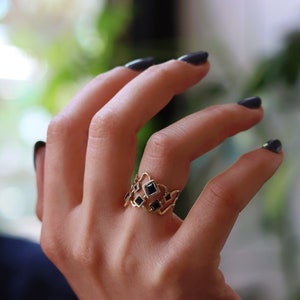 May include: A gold ring with a geometric design featuring black square stones.