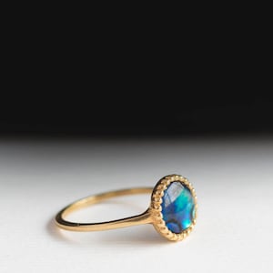 May include: A gold ring with a blue and green abalone shell set in a beaded bezel.