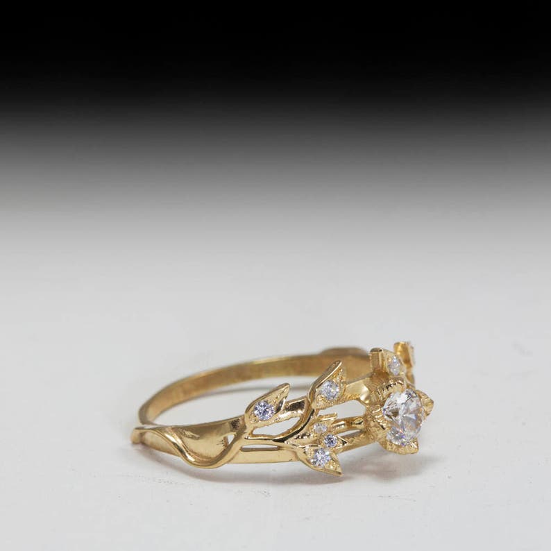 May include: A gold ring with a delicate floral design and a single round diamond in the center.
