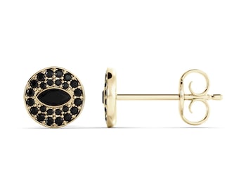 May include: A pair of gold stud earrings. Each earring features a circular design with a border of small black stones surrounding a central oval-shaped black stone. The earring posts are gold.