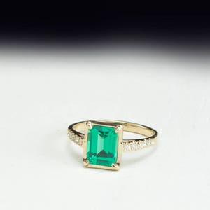 May include: A gold ring with a large emerald green gemstone and smaller diamonds set in the band.