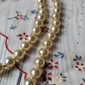 Collier ancien des années 1920 noué en fausses perles vieillies, longue ficelle de style Gatsby.