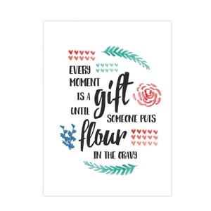 以下が含まれることがあります： 「Every moment is a gift until someone puts flour in the gravy」というテキストが書かれた白い長方形のプリント。テキストは黒い筆記体で、赤いハート、緑の葉、ピンクのバラの水彩アクセントが施されています。