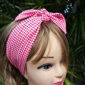 Puede incluir: Una diadema con estampado de cuadros rojos y blancos con un lazo anudado. La tela presenta un diseño de cuadros clásico. La diadema se lleva en un maniquí con cabello castaño claro.