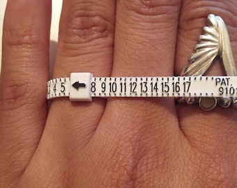 May include: A white plastic ring sizer with numbers 4.5 to 17, an arrow pointing to the left, and the text "PAT. 9101" on the right side.