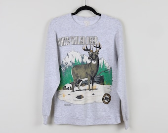 May include: Gray long-sleeve shirt with a white-tailed deer graphic. The deer is standing in a snowy forest with mountains in the background. The text "WHITE-TAILED DEER" is printed above the deer.