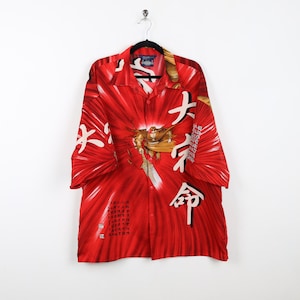May include: Red short-sleeved button-up shirt with a white and gold print of a warrior and Japanese characters. The shirt has a button-up collar and a button-up front.