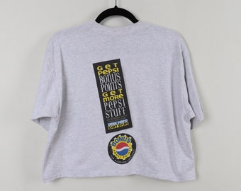 May include: A gray cropped t-shirt with a Pepsi logo and the text "Get Pepsi Bonus Points Get More Pepsi Stuff Drink Pepsi Get Stuff" printed on the back.