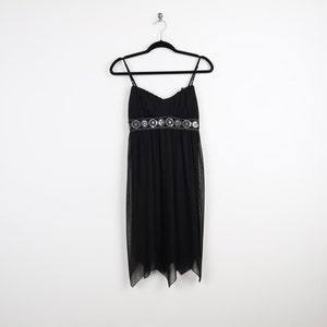 May include: A black sleeveless dress with a silver beaded waistband. The dress has a flowing skirt and a fitted bodice.