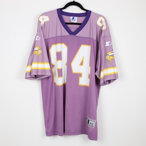 May include: A purple mesh sports jersey featuring the number 84 in white with yellow outlines on the front. The sleeves display a Viking helmet logo, white and yellow stripes, and the Starter brand logo. A Starter label is at the bottom hem.