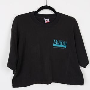 May include: Black cropped t-shirt with the text "University of Miami" and "School of Law/Banking/MBA" in blue.