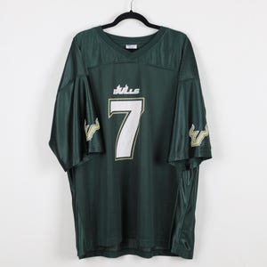 May include: Dark green mesh jersey with the number 7 in white and gold trim. The word "Bulls" is above the number. The jersey has gold accents on the sleeves. The jersey is hanging on a black hanger.