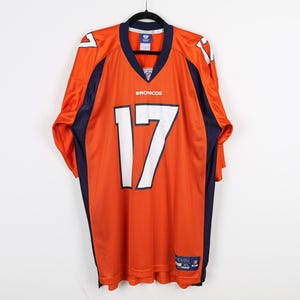 May include: Orange and navy blue football jersey with the number 17 and the word "Broncos" on the front. The jersey is size XL.